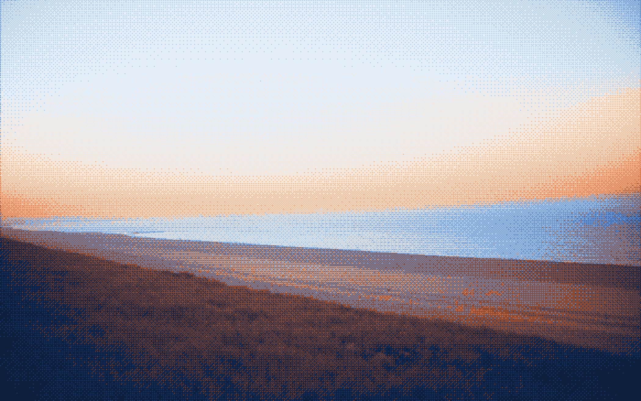 A shoreline beach at sunset in soft blue and peach light